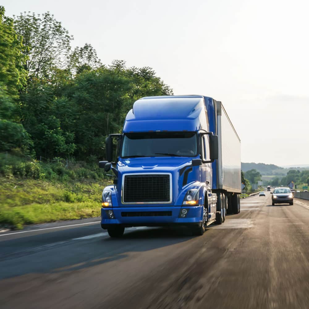 a blue diesel truck driving down a busy highway